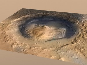 Gale Crater, the landing spot of NASA’s Curiosity Mars rover, has a three-mile-high mound at its center called Mount Sharp. The circle indicates the rover’s landing place. The blue line is its path. New research shows mounds like this may have been carved by wind over billions of years. Credit: NASA/JPL.