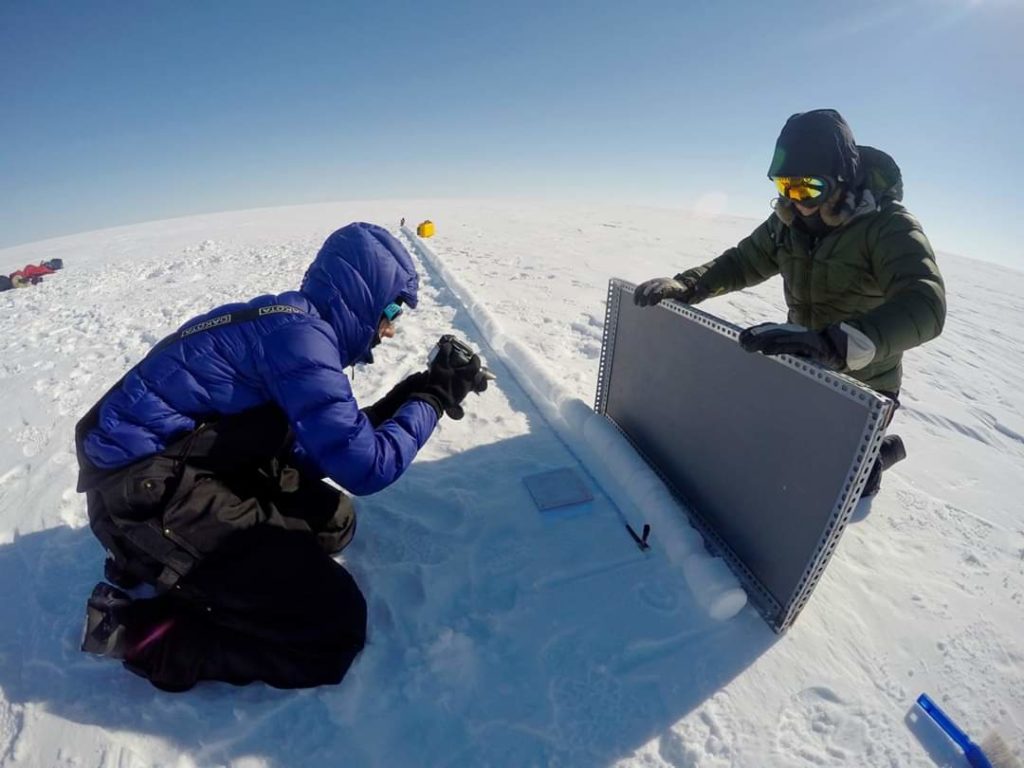 Researchers Colleen Mortimer and Anja Rutishauser photograph an ice core for visual inspection used to date the ice, on the Devon Ice Cap, Nunavut, in the Canadian Arctic. Credit: Alison Criscitiello