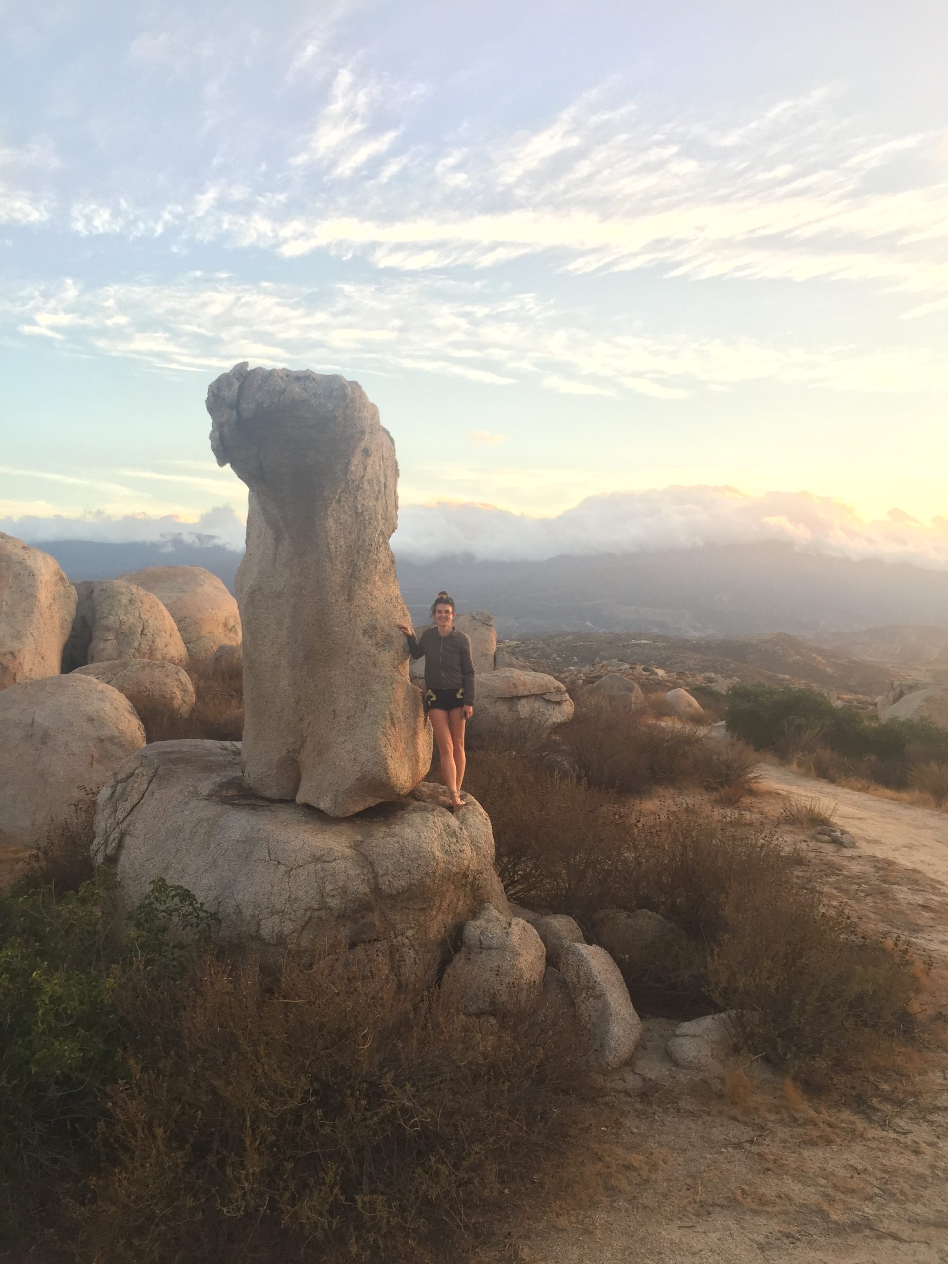 Anna Rood standing next to a tall, slender precariously balanced rock in Southern California. Cosmogenic surface exposure dating samples have been collected to determine its age, and a 3D model has been made to determine its probability of toppling due to earthquake ground shaking. Credit: Anna Rood & Dylan Rood, Imperial College London