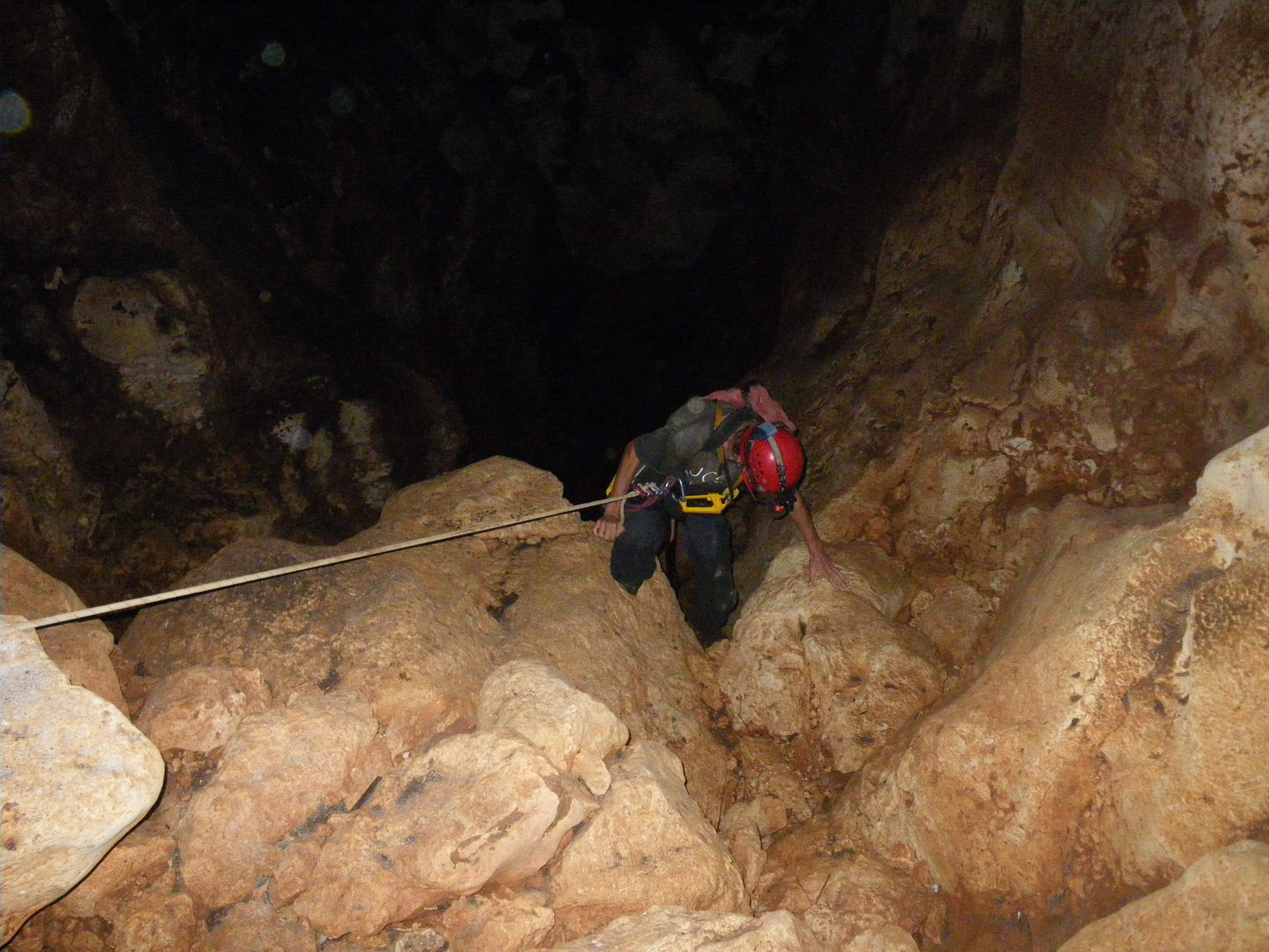 photograph of a man descenting into a vertical cave on a rope