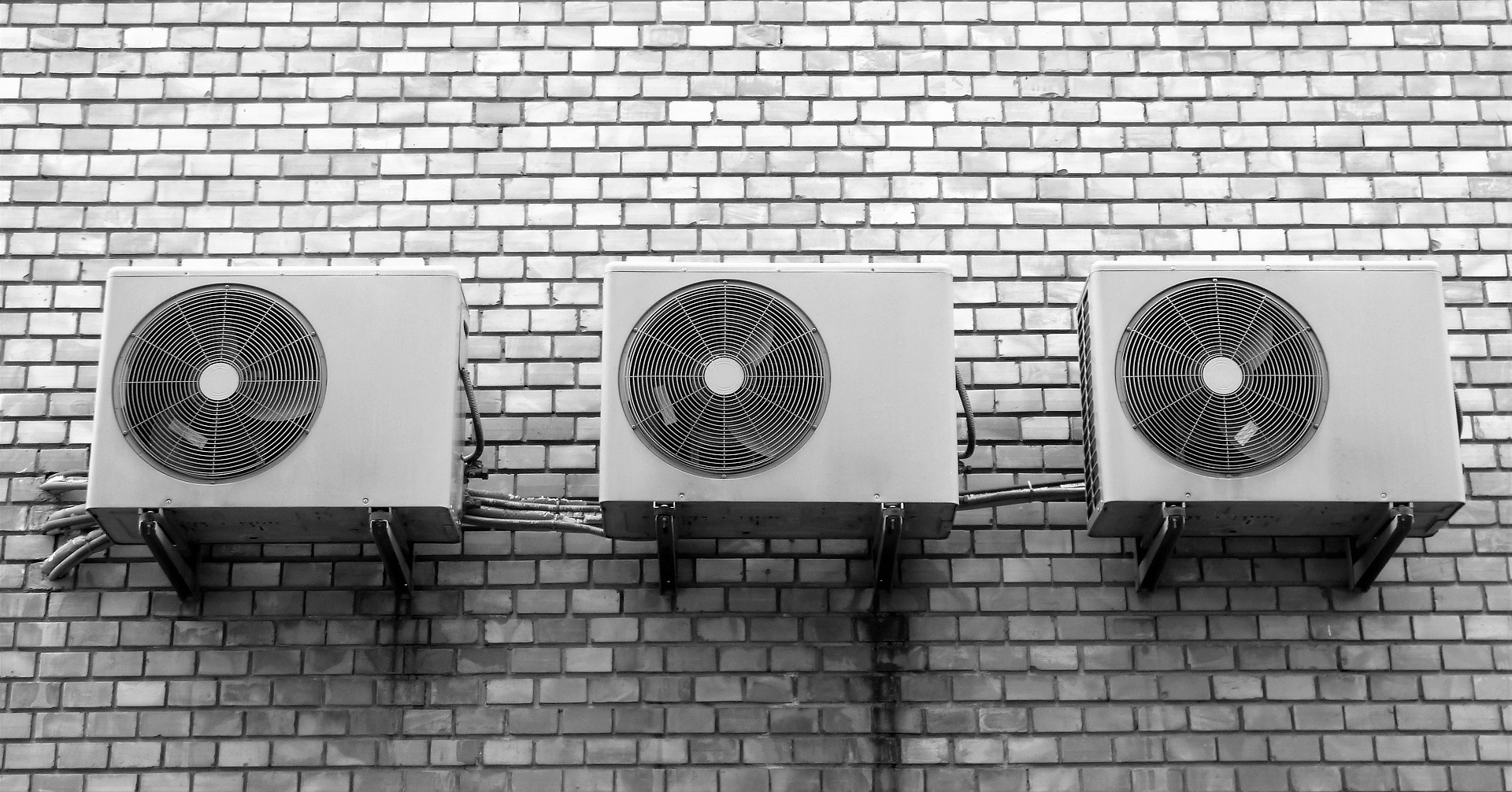 photograph of three AC units mounted on a brick wall
