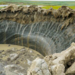 A large crater in the ground in the Siberian tundra.