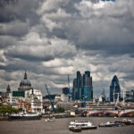 A view of London from the Thames River. Large storm clouds hang over the city.