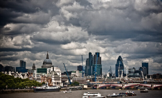 A view of London from the Thames River. Large storm clouds hang over the city.