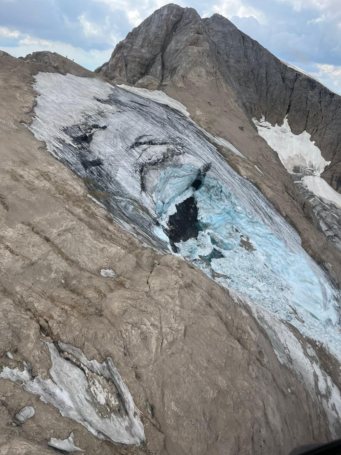 A caved-in portion of a glacier on a steep, rocky mountain slope