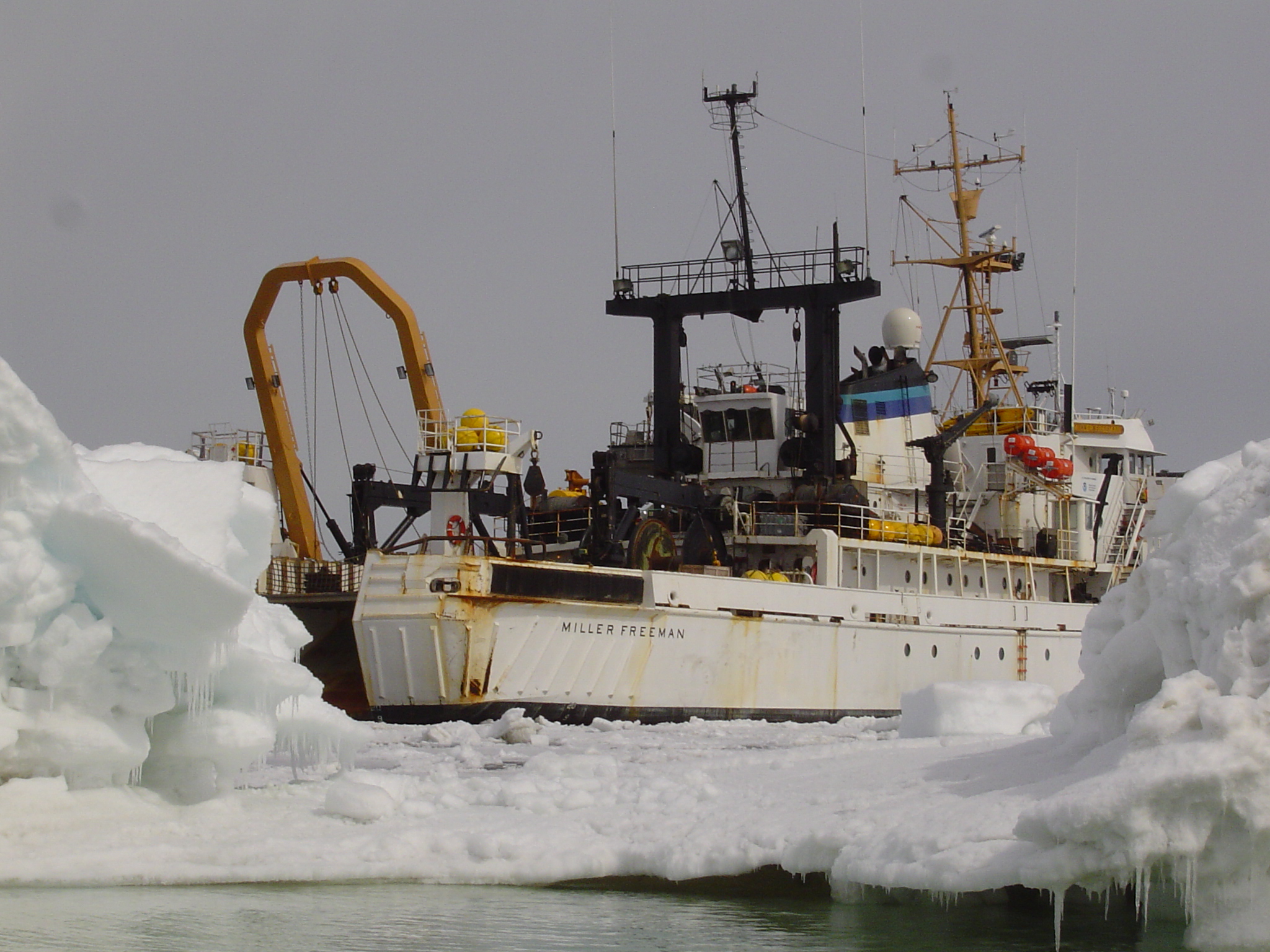 A research vessel at sea, surrounded by sea ice