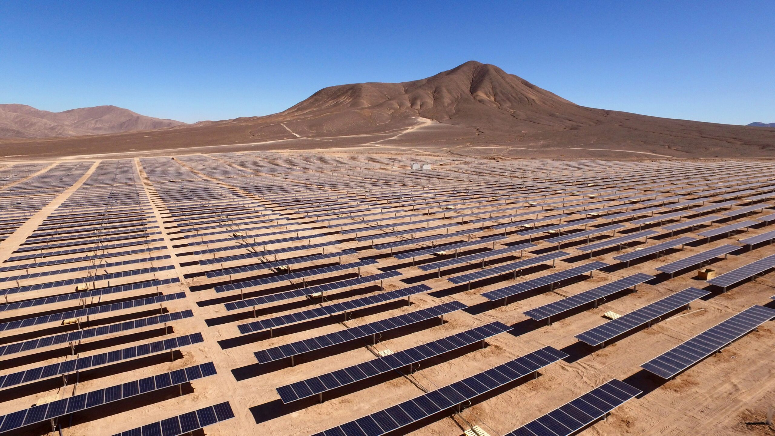 Rows and rows of solar panels in a dusty desert in Chile.